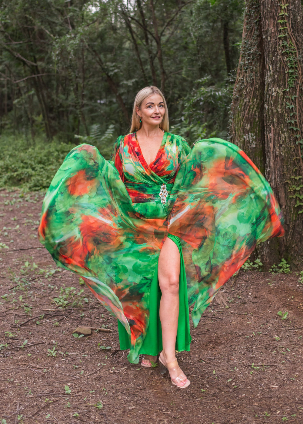 Woman in a green and red dress standing in a forest